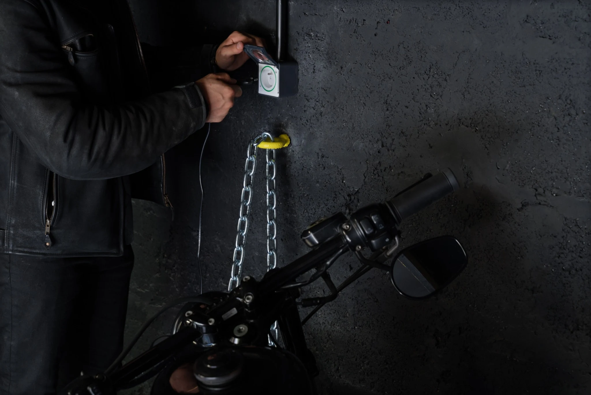 Accueil 74 Personne manipulant un branchement près d’une prise murale, d’une chaîne et d’une moto chez Black Garage.